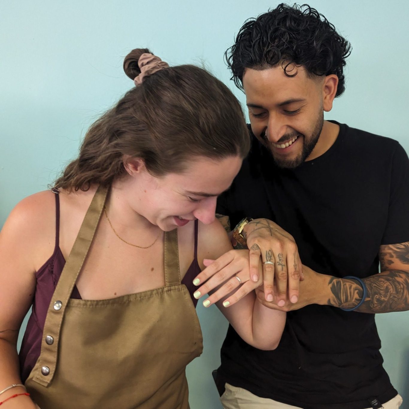 Fuego Eterno · Taller de alianzas en pareja Una pareja sonríe mientras muestra sus alianzas en las manos dentro del taller de joyería aiguaMarina joies.